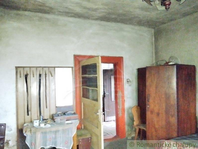 A room in a family house with older furniture, a wooden wardrobe, and open doors.