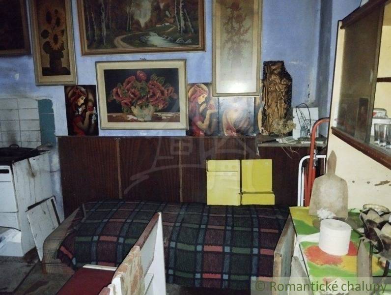 A room full of paintings, old furniture, and decorations in a village family house.