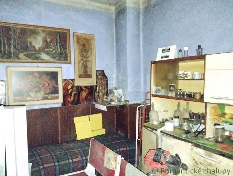 A room in a family house with vintage furniture, paintings, and shelves full of trinkets.