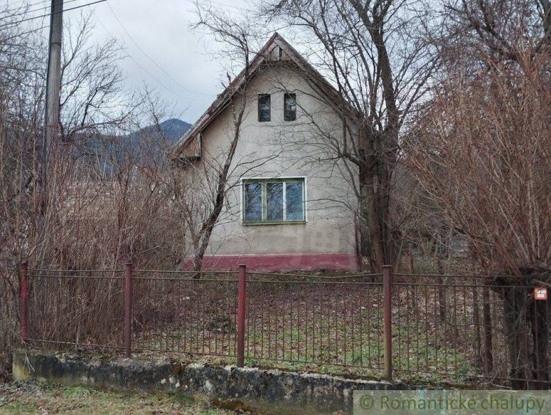 An old family house is surrounded by trees and a fence.