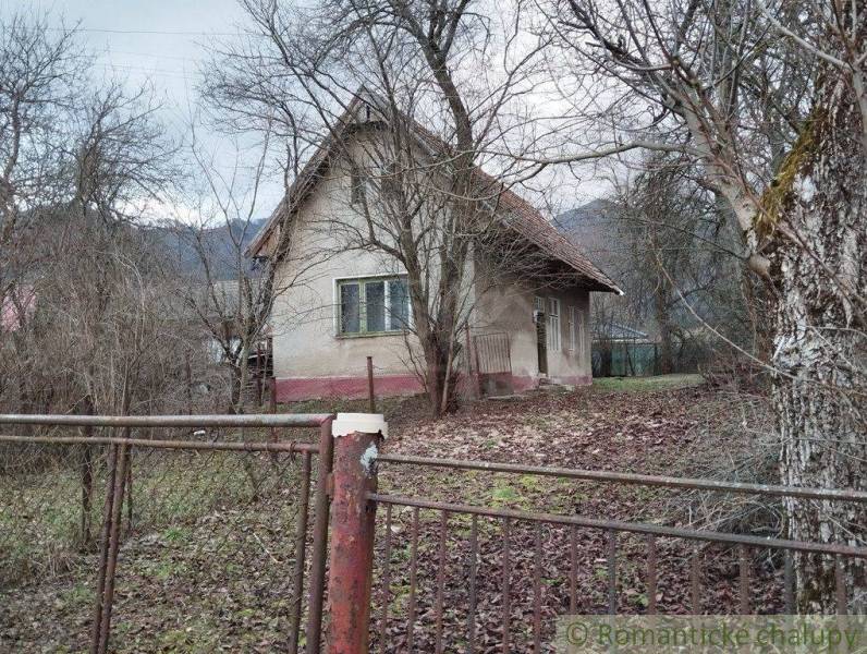 A family house surrounded by trees, a fence, and fallen leaves, a peaceful natural environment.