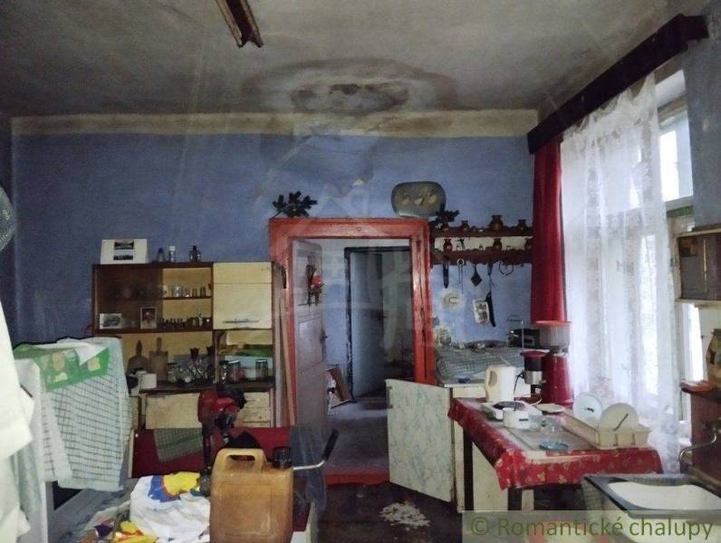 An old family house with blue walls, curtains, and antique furniture in the interior.