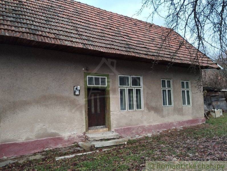A family house with plaster, windows, and wooden doors under a pitched roof.