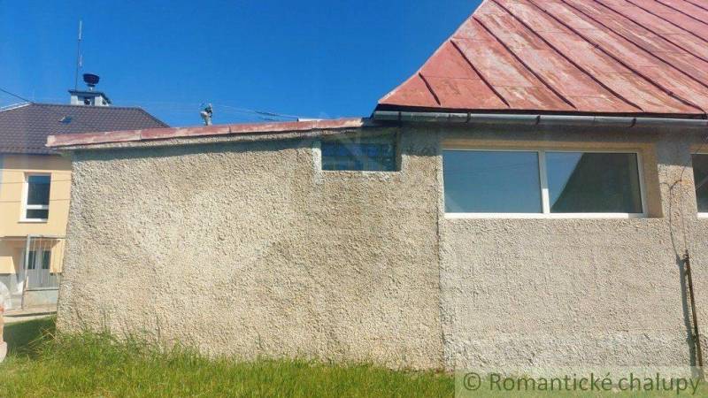 A family house with a gable roof, plaster, and a grassy area, on a sunny day.