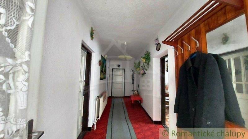 A narrow hallway in a family house with a red carpet and a wooden coat rack.