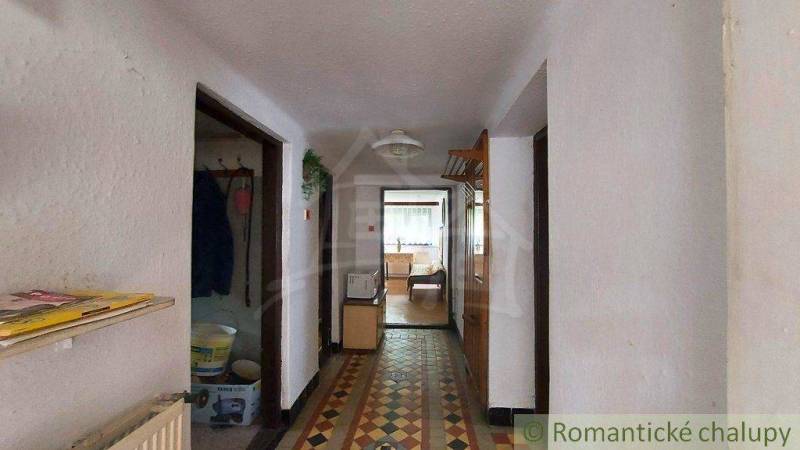 A hallway in a family house with a tiled pattern on the floor, leading to a sunny room.