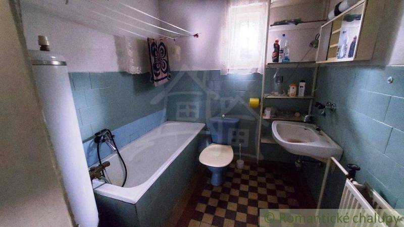Bathroom with a bathtub and a sink, part of a family house, also includes a radiator.