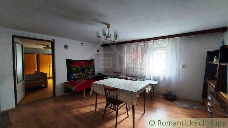 Dining room with a wooden table, chairs, fireplace, leading to the bedroom and family house.