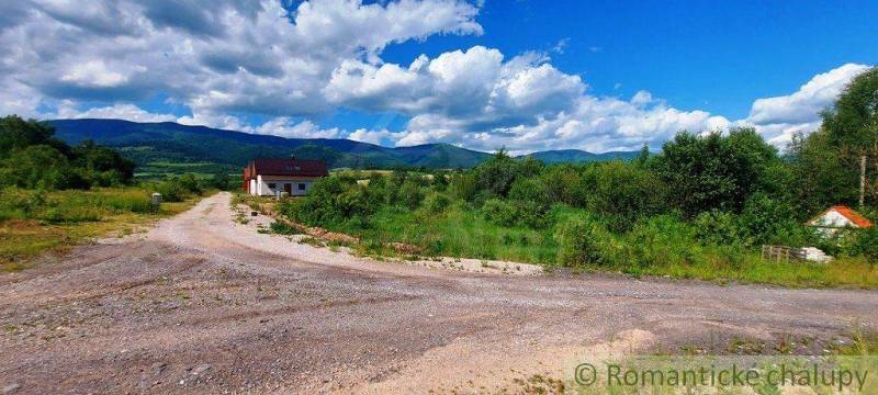 A landscape with a house and recreational land surrounded by mountains and a sky with clouds.