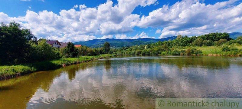 A lake with hills, trees, and houses; recreational nature grounds in the background.