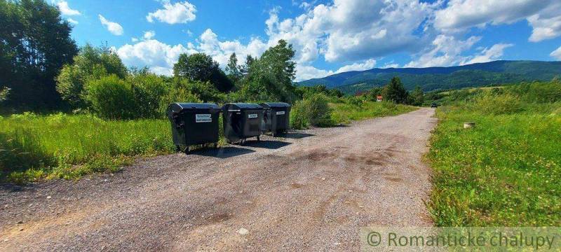 A rural landscape with waste containers, surrounded by greenery, suitable for living and plots.