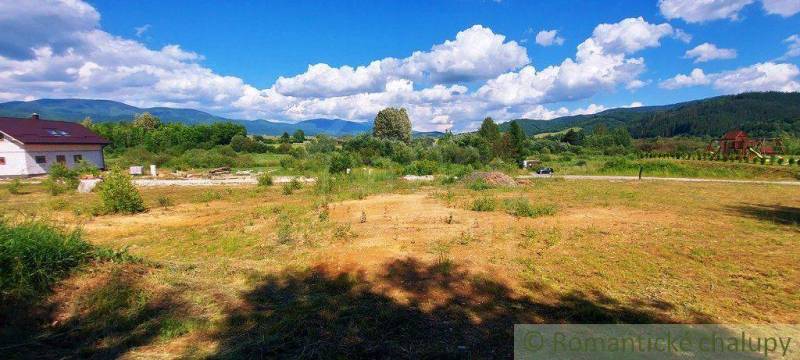 A grassy area and a house, mountains in the background, an ideal location for recreational plots.