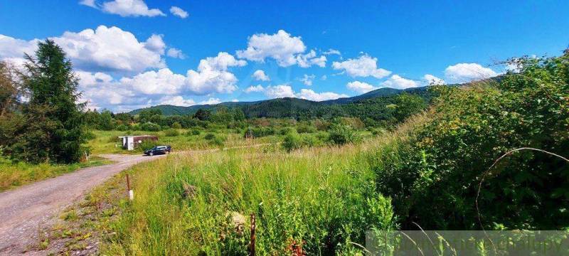 Hilly landscape with forests and recreational areas, blue sky with clouds.