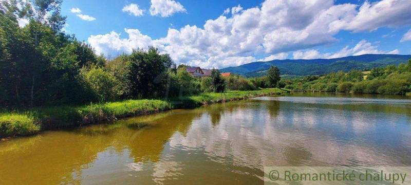 Green trees and a river with clouds, mountains, recreational areas ideal for relaxing by the water.