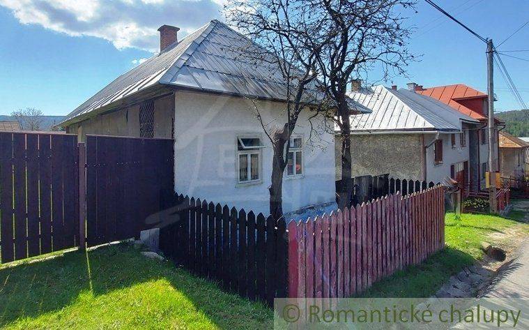 A house with a metal roof and a fence by the road, suitable as a unique property for cottage owners.