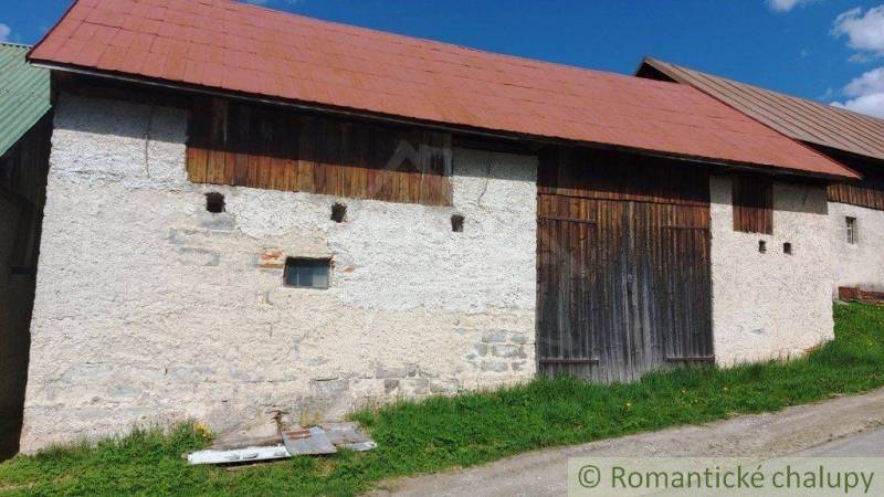 The image shows an old shed with a wooden gate and stone walls.