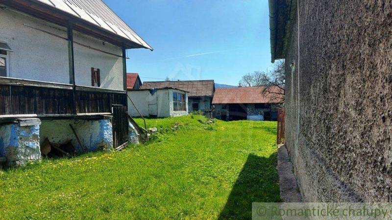 A large yard with an old cottage, green lawn, two shelters, and peculiar properties.
