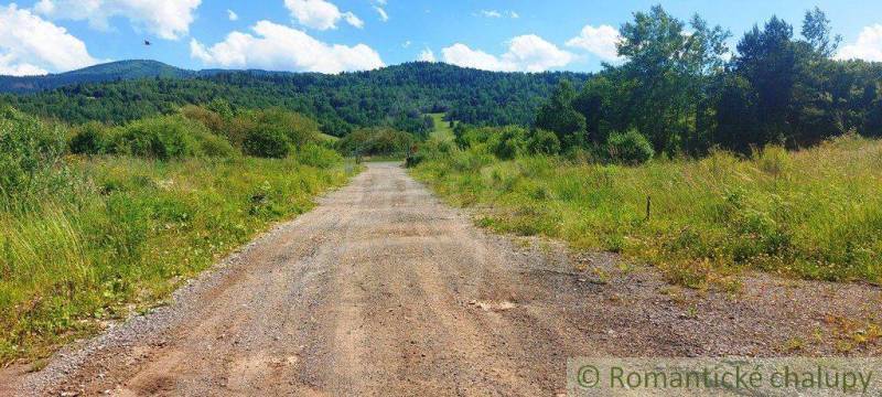 The path leads through green countryside to wooded hills, ideal for recreational living.