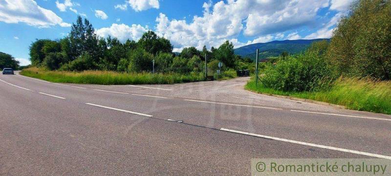 A road with a view of fields with nature and mountains in the distance.