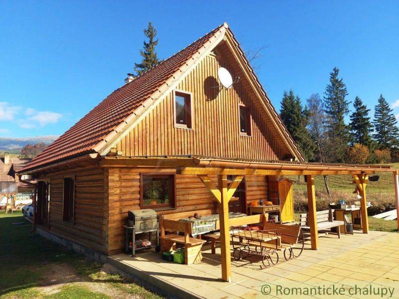 A cottage in nature with wooden decor, a large terrace, and a grill in the countryside.