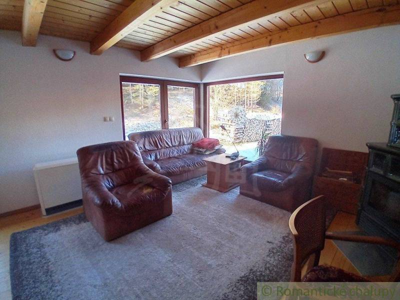 A living room in a cabin with a wooden ceiling and leather furniture.