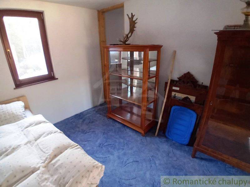 A room in a cottage with a bed, a display cabinet, and wooden furniture with a natural atmosphere.