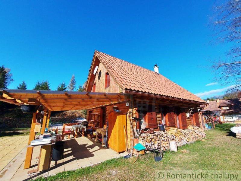 Traditional wooden cottage in the countryside with a terrace, surrounded by nature and wood.