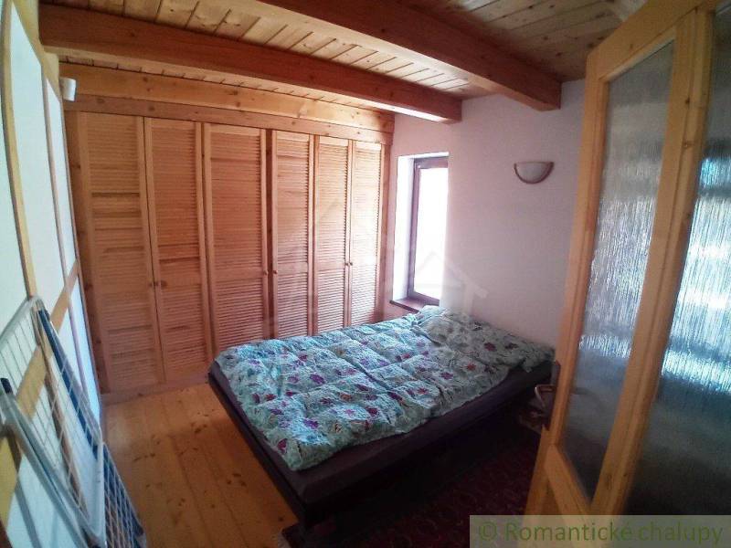 There is a cozy bedroom in the cottage with a wooden ceiling and a built-in wardrobe.