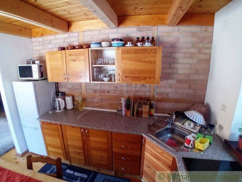 A kitchen in a cabin with wooden cabinets and equipment on a brick wall.