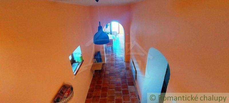 A hallway in an ancient house with peculiar architectural openings and a vaulted ceiling.
