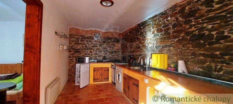 A kitchen with a unique design, stone walls, wooden details, and a rustic atmosphere.