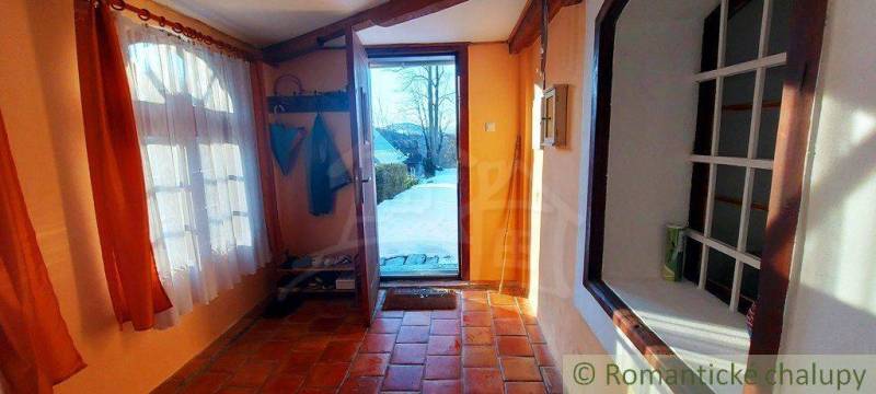 Entrance hall with a brick floor, curtains, and a view of a natural scene.