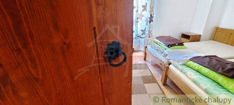 A rustic furnished room with a wooden bed and heavy doors, peculiar properties.