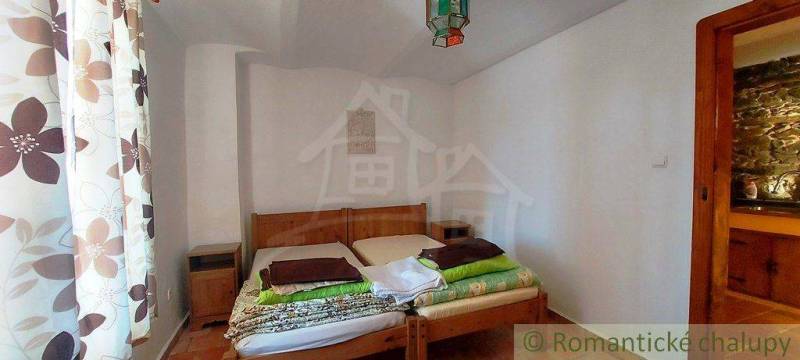 A bedroom with floral curtains, a wooden bed, peculiar property, and an original lamp.
