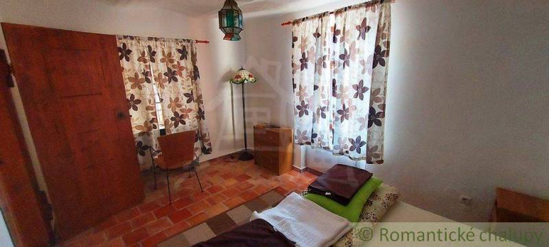 A room with tiled flooring, floral curtains, a lamp, and rustic furniture, suitable for unique properties.