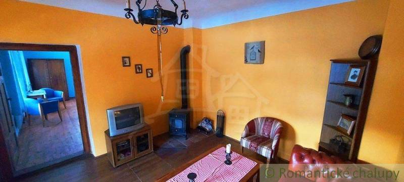 Living room with orange walls, antique furniture, retro television, and rustic decoration.