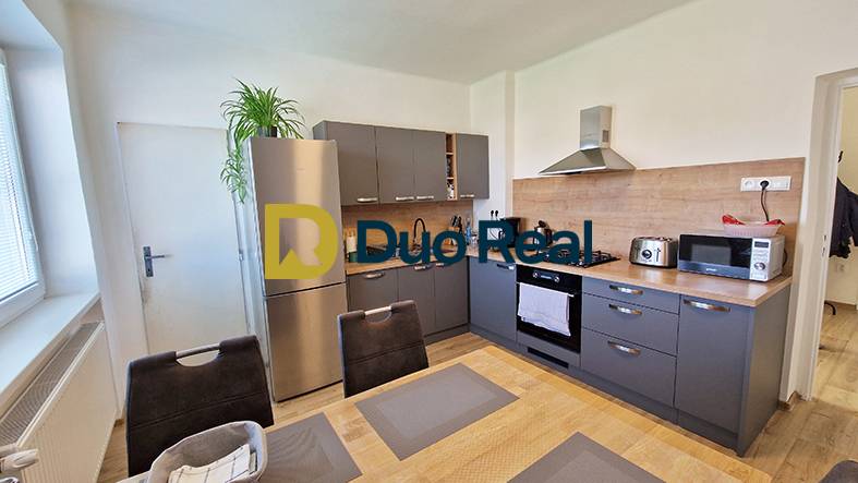 A kitchen in a family house with a kitchen unit, appliances, and a dining table.