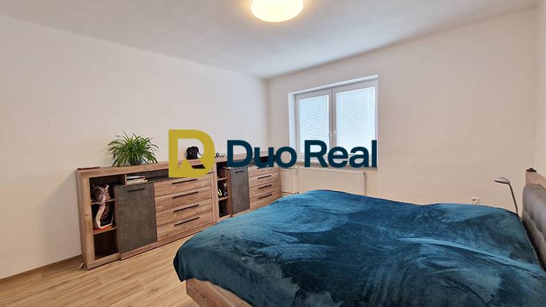 Bright bedroom with a large bed and a dresser in a family house.