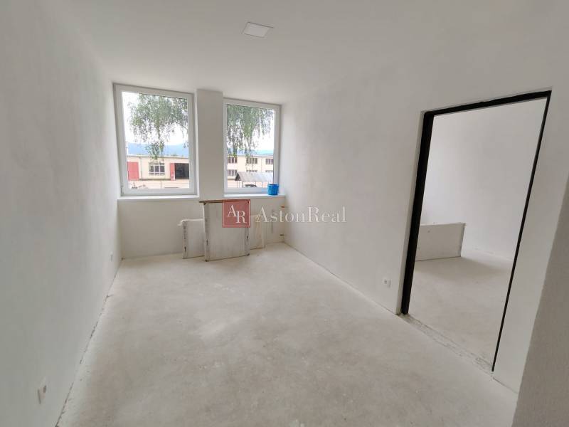 A spacious room under renovation inside a 3-room apartment with large windows.