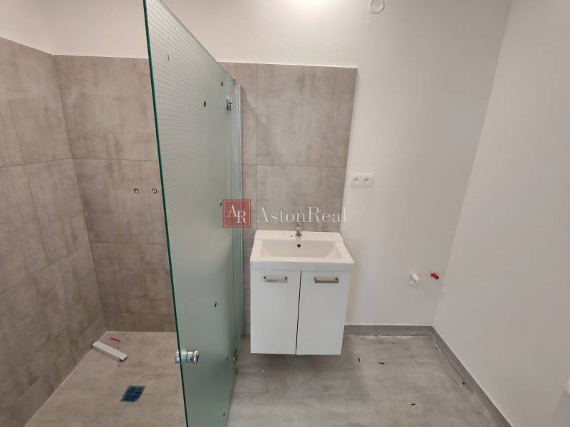 A bathroom in a 3-room apartment with a sink and a glass shower screen.