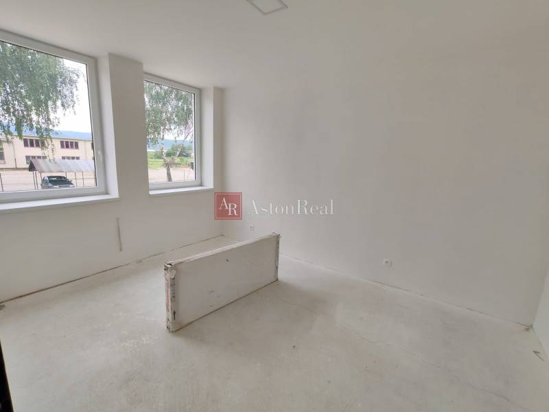 Empty room in a 3-bedroom apartment with light walls and two large windows.
