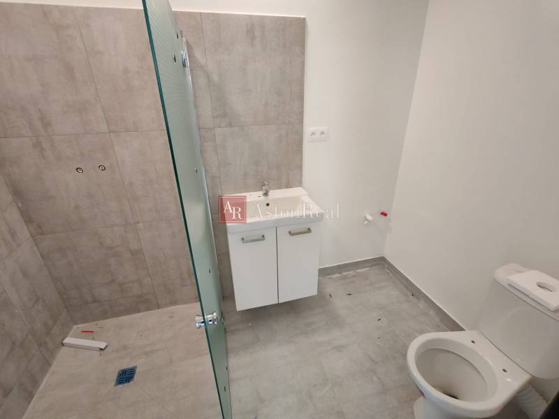 A bathroom in a 3-room apartment with a toilet, shower, and sink.