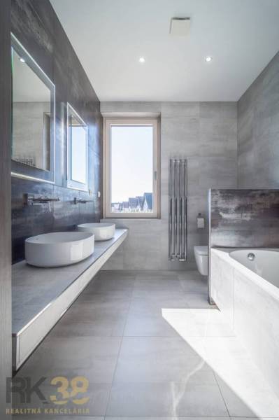 A bathroom in a family house with two sinks, a bathtub, and a large window.