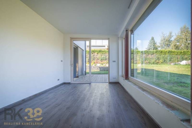 Interior of a family house with wooden flooring and a view of the garden through a large window.
