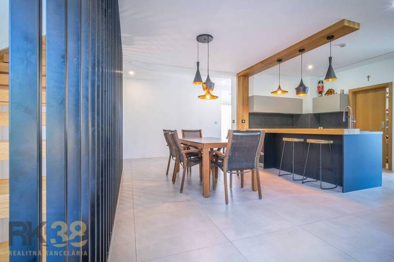 Dining area and bar counter in a family house with wooden furniture and pendant lamps.