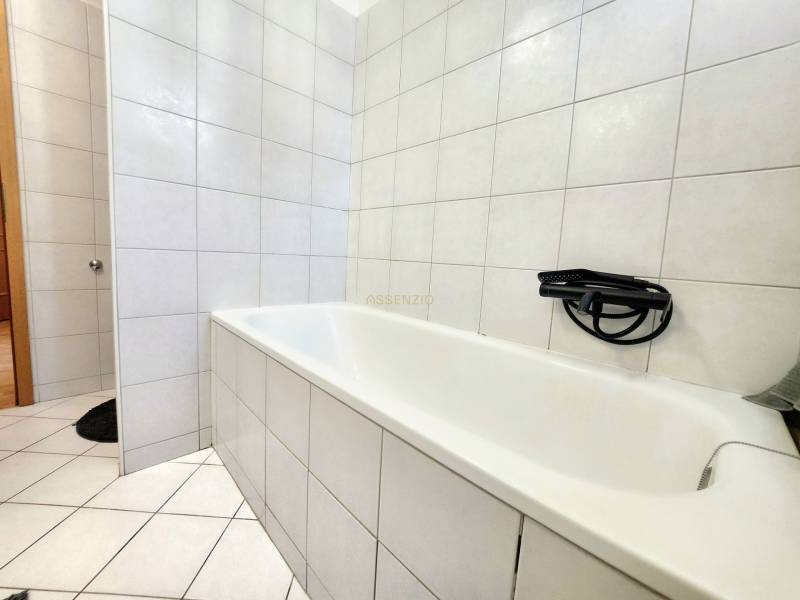 Bathroom with a shower head and tiles in a studio apartment.