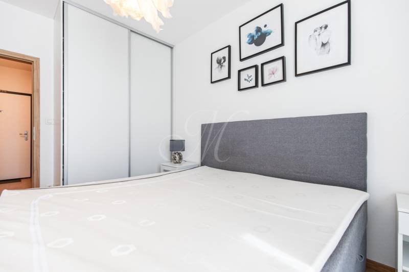 Bedroom in a 3-room apartment with a bed, lamp, and paintings on the wall.