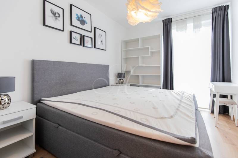 A bedroom in a 3-room apartment with a bed, nightstands, and paintings on the wall.