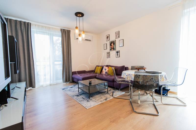 Living room with a purple sofa and a dining table in a 3-room apartment.