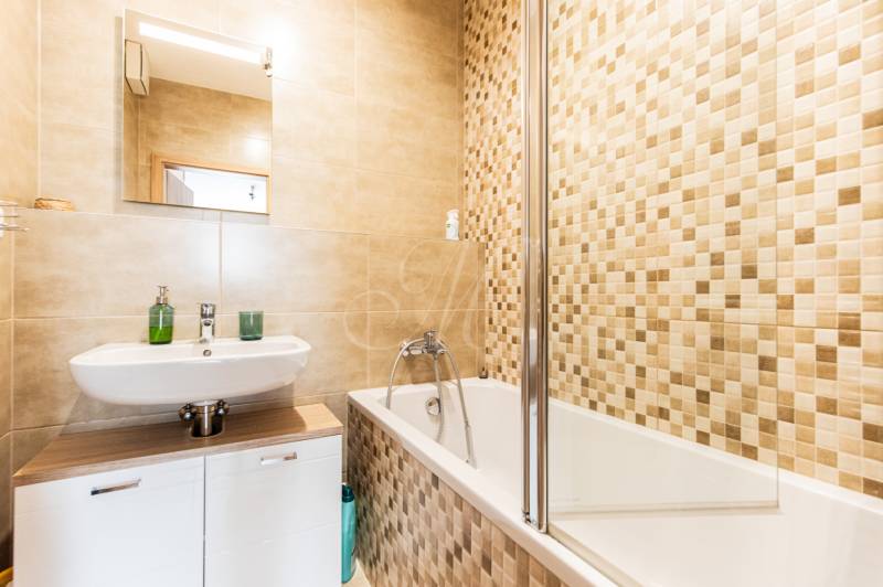 A bathroom with a shower and a sink in a 3-room apartment, tiled.